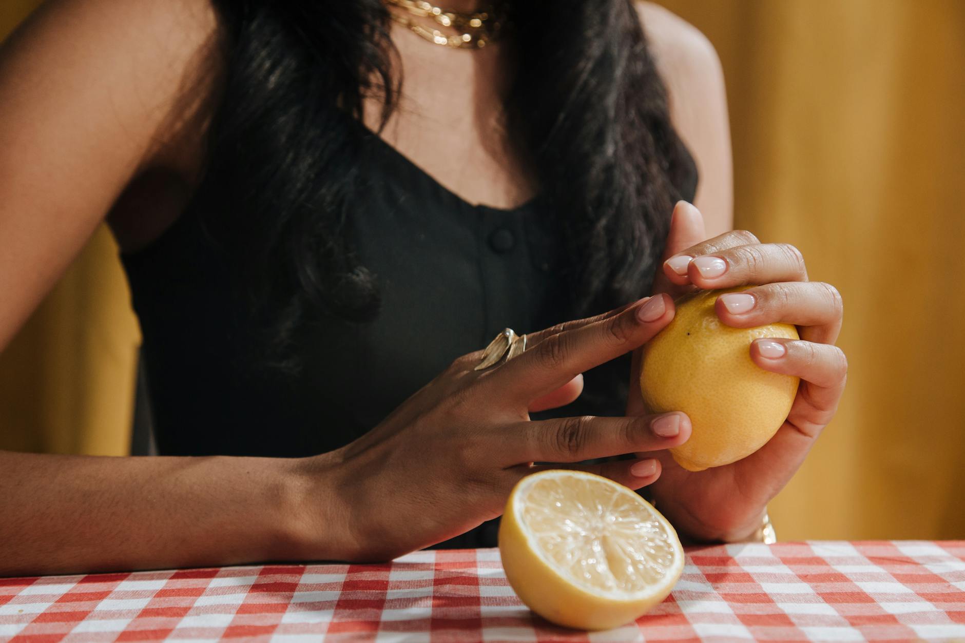 A hand holding a fresh lemon against a bright yellow background, symbolizing fresh sensation and renewal