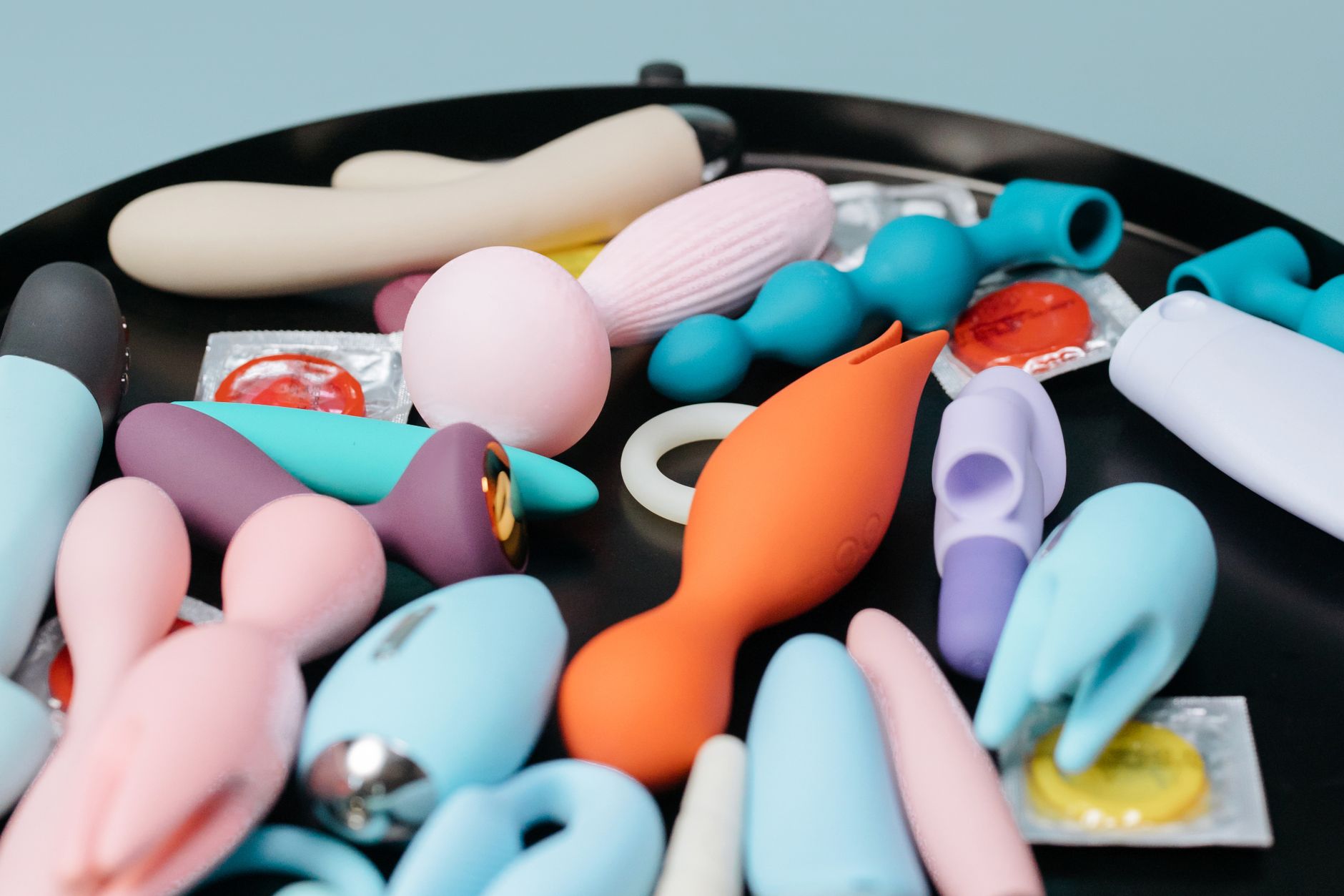 An array of vibrant clitoral vibrators displayed on a black surface, showing diverse shapes and colors designed for various stimulation preferences.