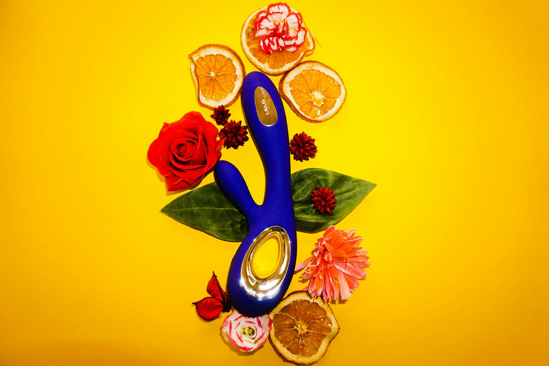 A lemon vibrator surrounded by flowers and citrus on a bright yellow background