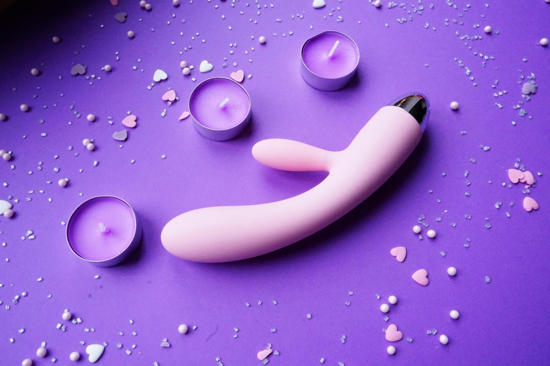Lemon vibrator on a purple background with heart confetti and candles for a romantic vibe